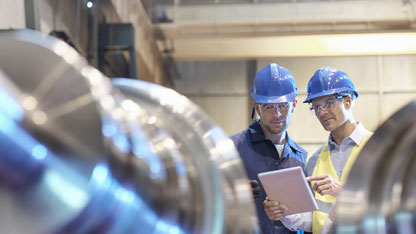 Inginerii inspectează rolele de oțel finite în fabrica de inginerie